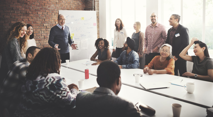 A group of employees and managers gathered in a conference room smiling and having a leadership development session